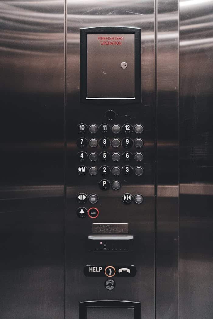 our-values Close-up of a metallic elevator control panel featuring buttons and digital display.
